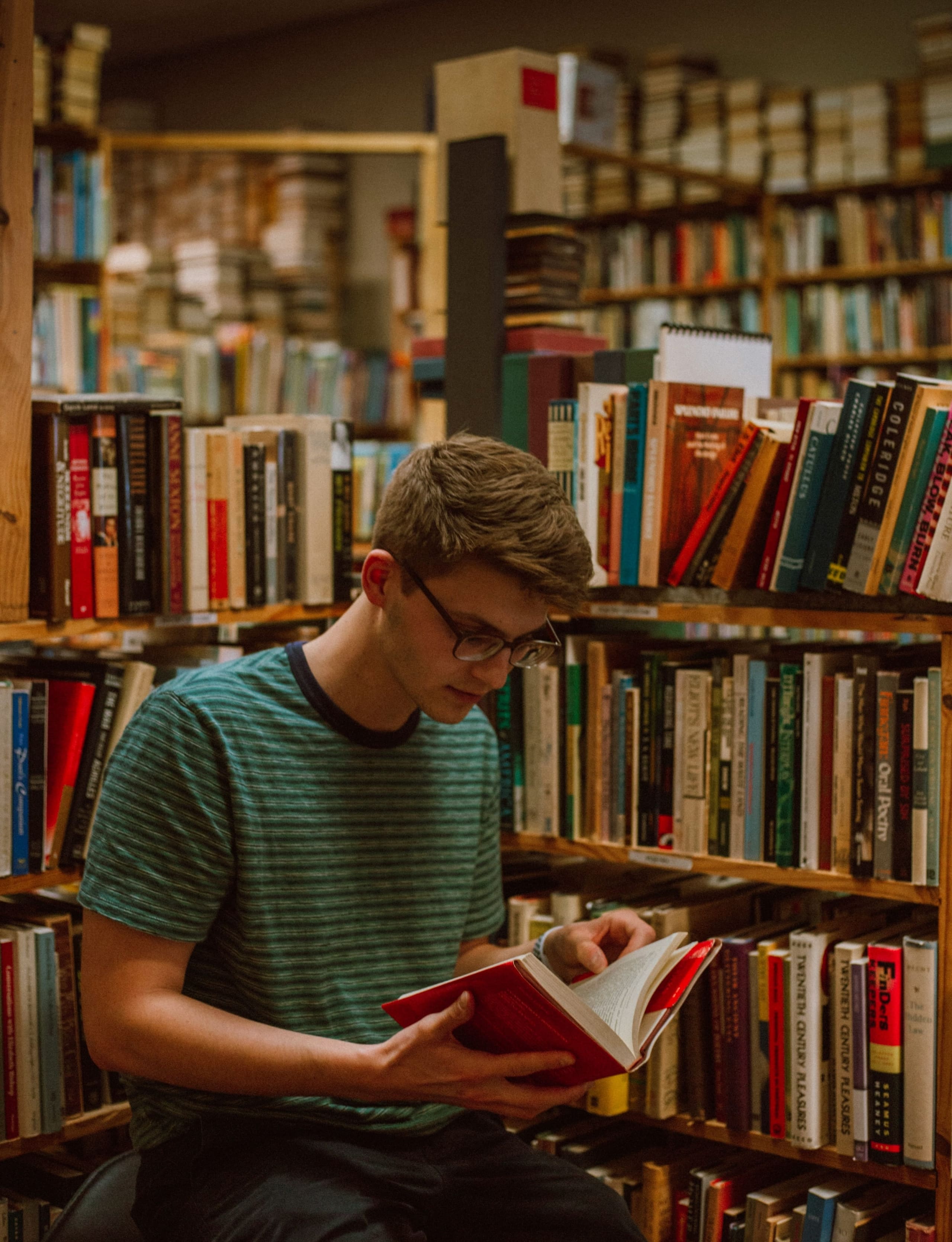 Étudiant lisant un livre à côté d'une collection d'œuvres littéraires